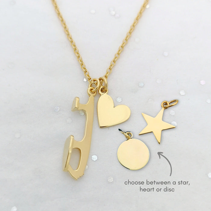 Gold necklace with various charms including a heart, star, and disc on a light gray background.