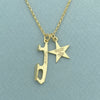 Gold necklace with a star and an ice skate blade charm, both charms are engraved on a pale green background