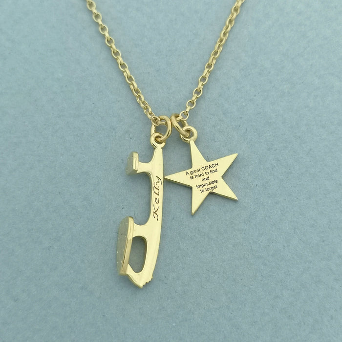 Gold necklace with a star and an ice skate blade charm, both charms are engraved on a pale green background