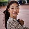 image of a girl wearing gold ice skating stud hoops featuring tiny ice skate blades