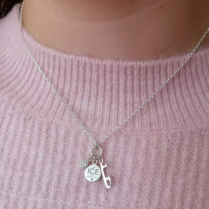 girl in a pink jumper wearing a silver happy place ice skating necklace featuring a motto, skate blade and a sparkly stone