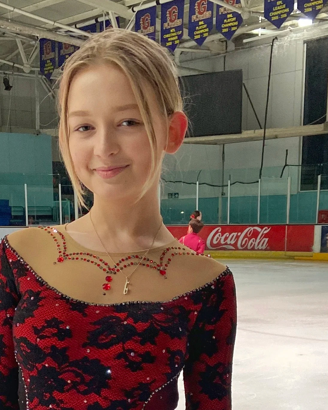 figure skater in a red dress wearing a personalised gold ice skating necklace