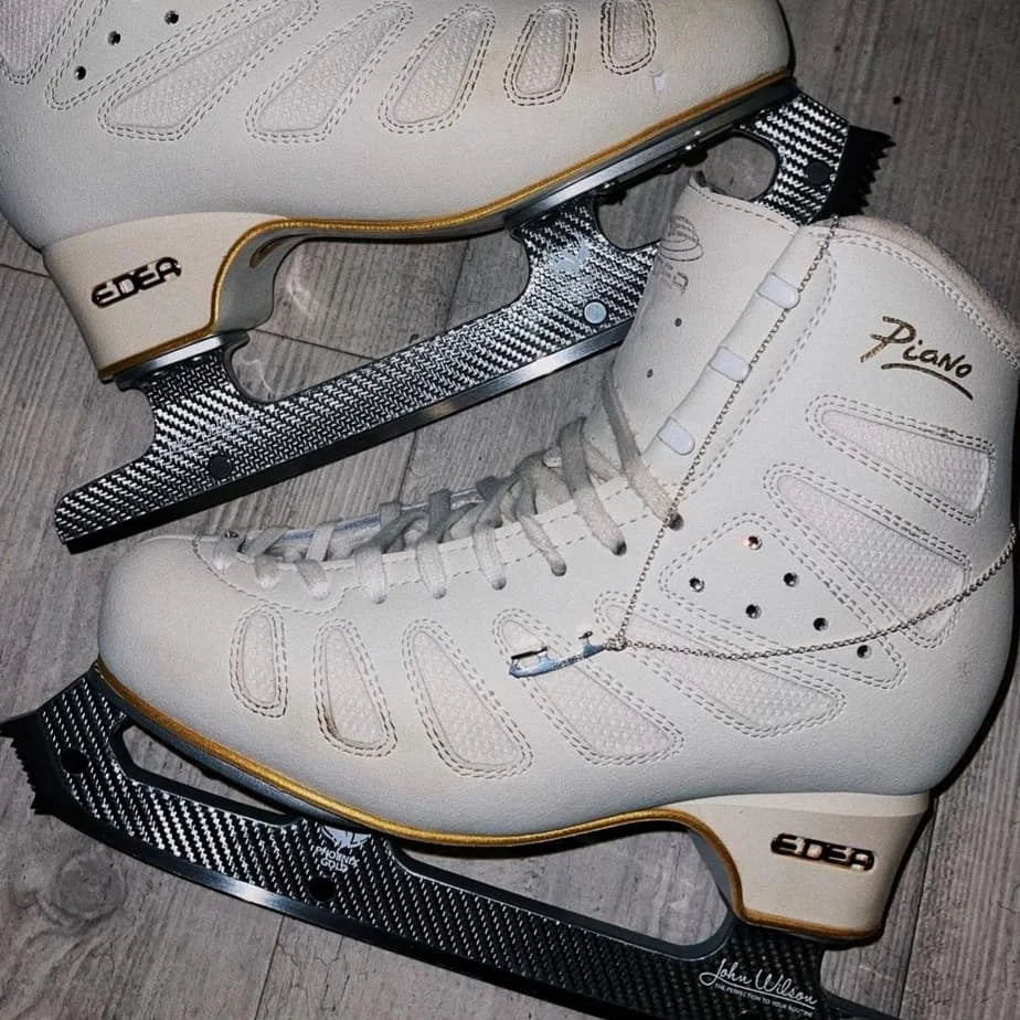 image of a pair of figure skating boots with a silver ice skating necklace draped on the top of one of the boots