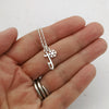 silver ice skate blade and snowflake necklace being held in a hand