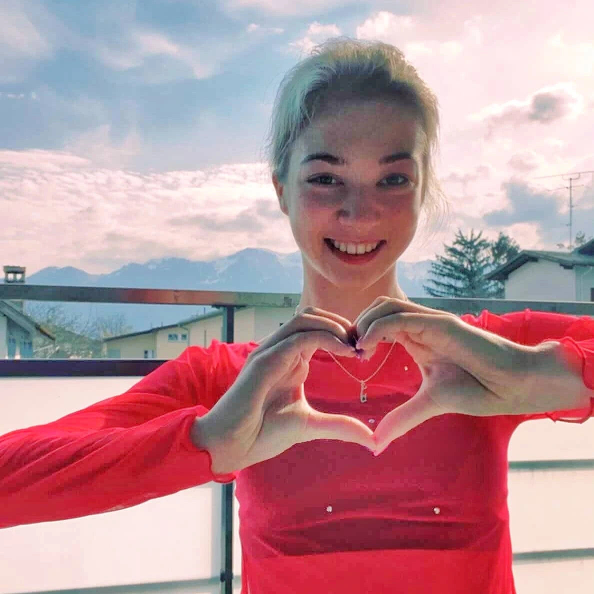 figure skater olga mikutina in a red top wearing a silver ice skate blade necklace