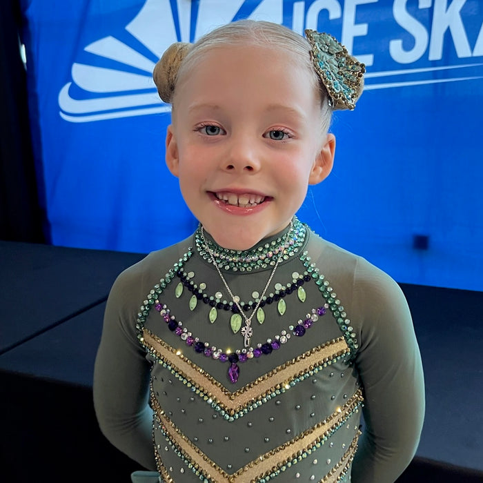 Young female Figure skater in a sparkly ice skating dress wearing a personalised silver skate blade and snowflake ice skating necklace