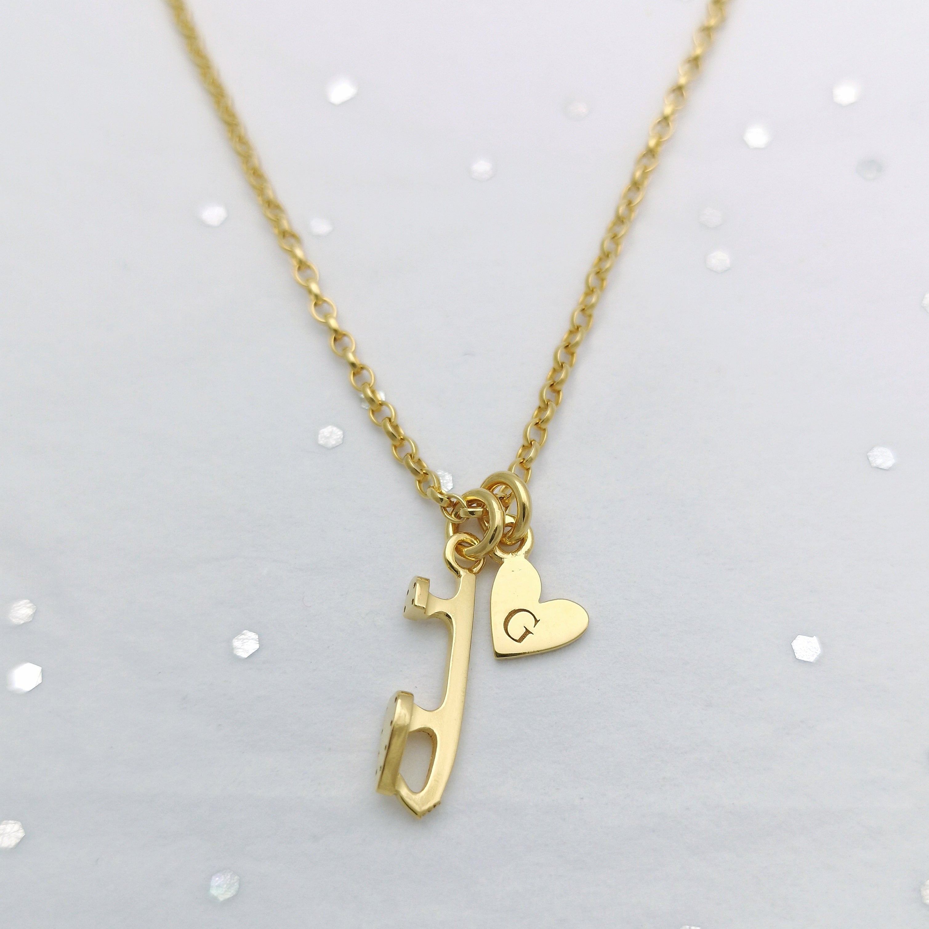 gold chain necklace on a sparkly background with a gold ice skate charm and a personalised heart charm