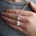 close up of a personalised silver ice skating necklace with a hand behind for scale