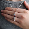 close up of a personalised silver ice skating necklace with a hand behind for scale