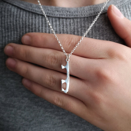 close up of a personalised silver ice skating necklace with a hand behind for scale
