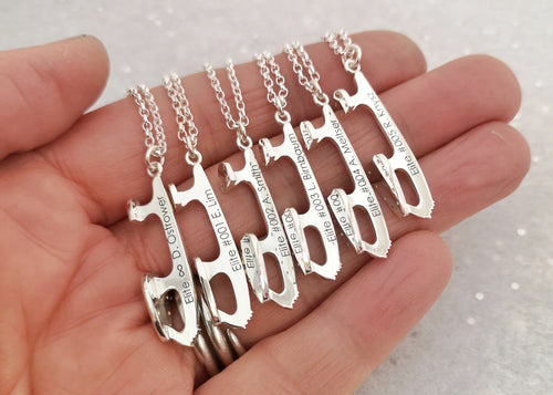 close up of six personalised ice skate blade necklaces being held in a hand