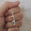 hand holding a personalised silver ice skate blade charm necklace, the name reads Ale Cat