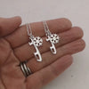 video of a hand holding two necklaces with skate blade and snowflake charms