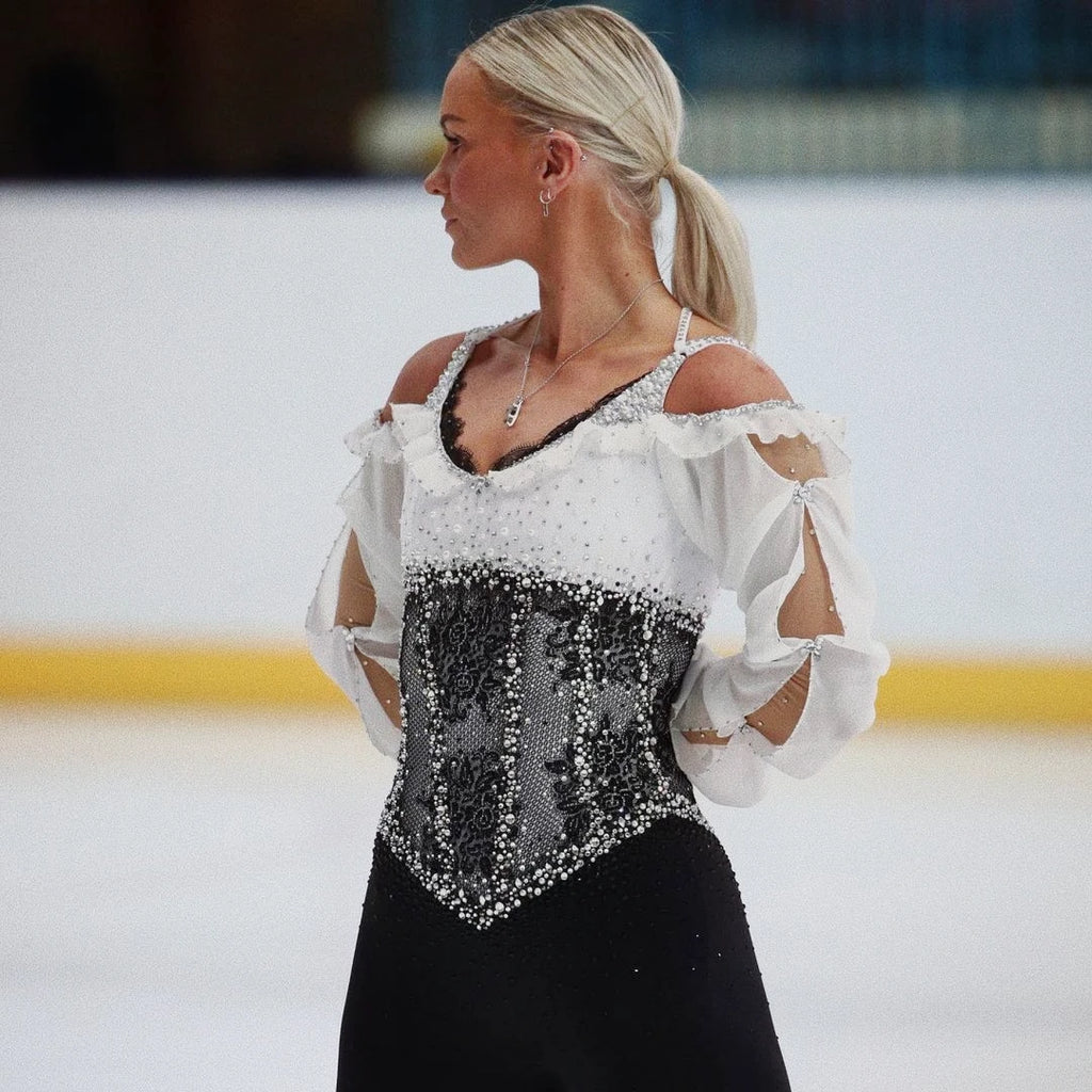 female skater on ice wearing a sparkly dress and silver hoop earrings with tiny ice skate blade charms
