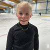young figure skater on ice in a black top wearing a silver ice skating charm necklace