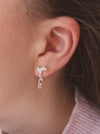 close up of a girl wearing silver ice skate blade and heart earrings