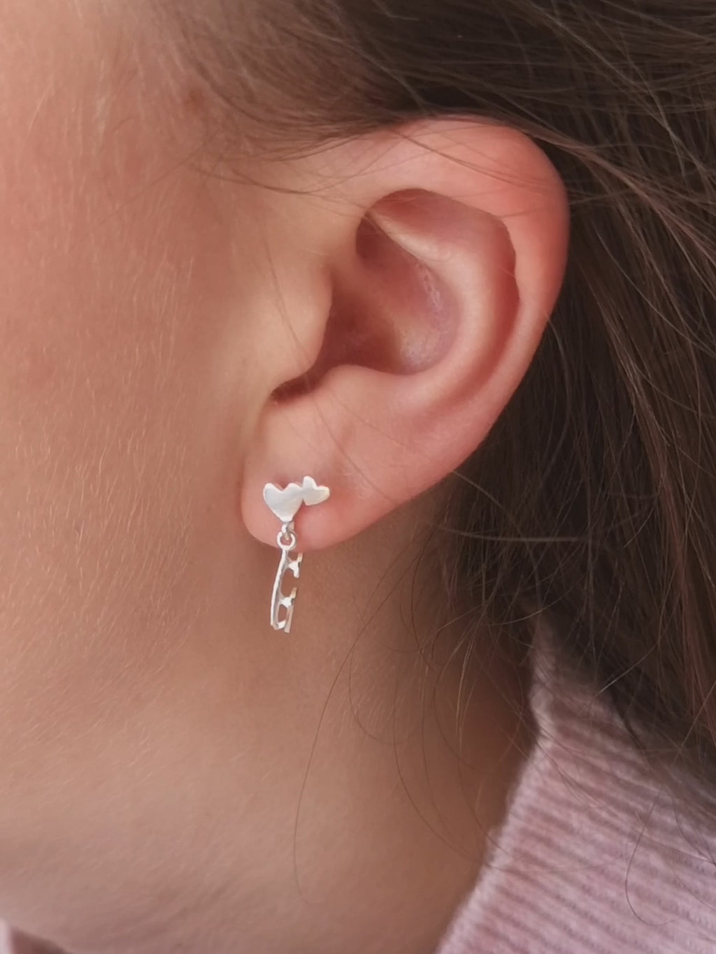 close up of a girl wearing silver ice skate blade and heart earrings