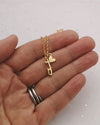 hand holding a gold necklace featuring a personalised heart and an ice skate blade charm