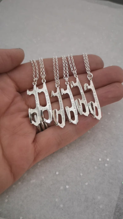 hand holding six personalised silver ice skating necklaces