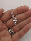 mini snowflake and ice skate blade necklade being held in a hand