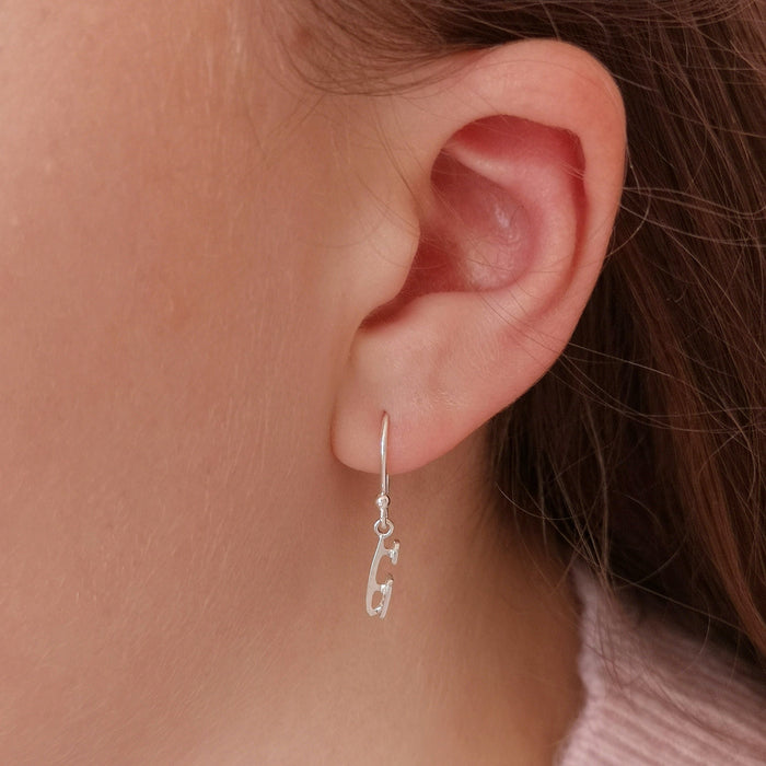 close up of a girl wearing a silver ice skating blade earrings