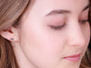 close up image of a figure skater wearing silver shine bright ice skating earrings which feature tiny skate blades and stars