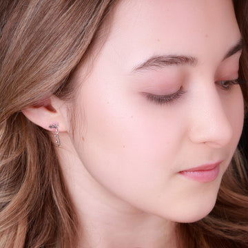 close up image of a figure skater wearing silver shine bright ice skating earrings which feature tiny skate blades and stars