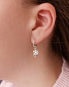 close up of a girl wearing a silver ice skate blade and snowflake hoop earring