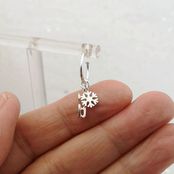 hand showing a silver ice skate blade and snowflake hoop earring