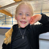 Young girl at an ice rink wearing a Snowflake Ice Skating Necklace | Ice Skating Jewellery
