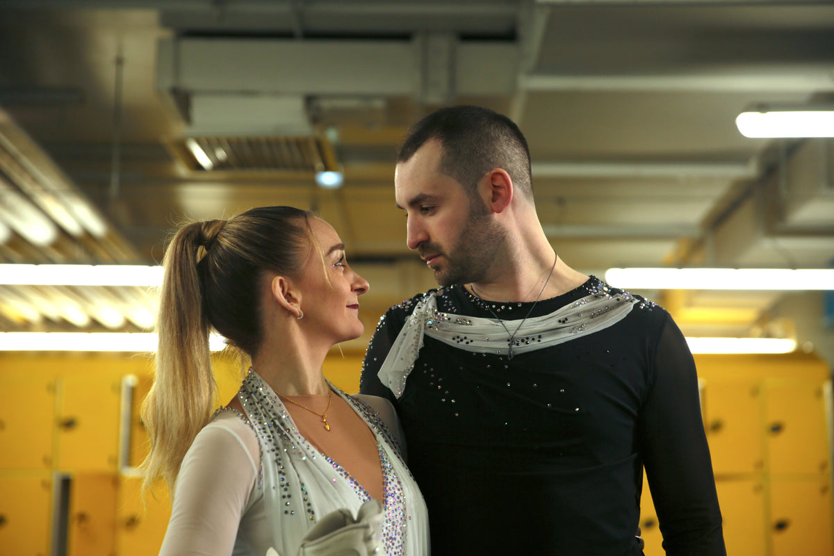 Two figure skaters in a locker room setting