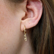 Close up image of Gold Ice Skating Stud Hoop Earrings being worn in the ear