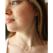 close up of a girl wearing a gold necklace featuring star and ice skate blade charms