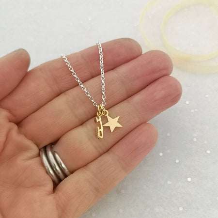 A sterling silver bracelet with a gold-plated ice skate blade charm and a star charm being held in a hand for scale.